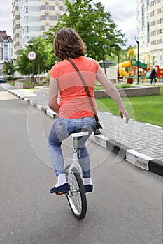 Woman rides monocycle in yard of residential photo