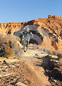 A woman rides a mountain bike down a trail below Gooseberry mesa in the Southern Utah desert