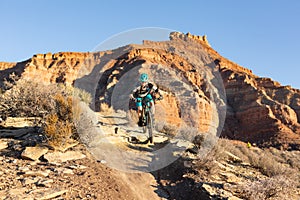 A woman rides a mountain bike over a small drop on the Jem trail below Gooseberry mesa in Southern Utah