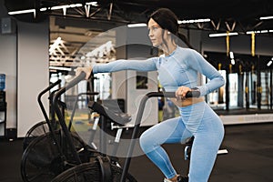 Woman riding on air bike in gym. .Girl using exercise bike for cardio training in the crossfit studio.