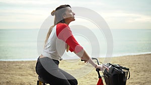 Woman riding bicycle along beach sand at summer time