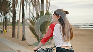 Woman riding bicycle along beach sand at summer time