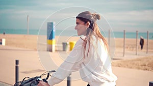 Woman riding bicycle along beach sand at summer time