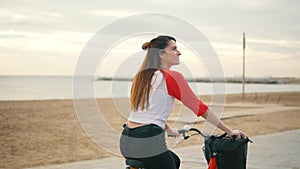 Woman riding bicycle along beach sand at summer time