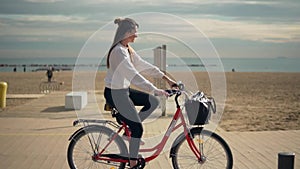 Woman riding bicycle along beach sand at summer time