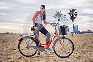 Woman riding bicycle along beach sand at summer time