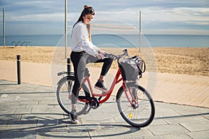 Woman riding bicycle along beach sand at summer time