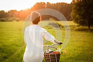 Woman riding bicycle with the basket of fresh food.