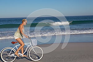 Woman riding bicycle on beach in the sunshine