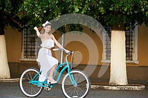 Woman riding on bicycle in city at background trees, walls