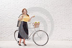 A woman is riding a bicycle with a crop of apples in a basket.