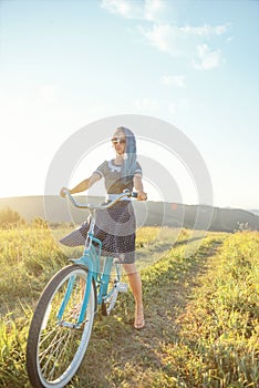 Woman riding bicycle cruiser on countryside path in summer.