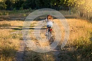 Woman riding bicycle on dirt road at meadow