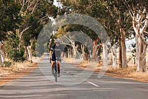 Woman riding bicycle on empty road. Cyclist rides her bike through empty countryside highway