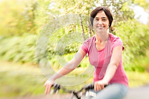 Woman riding bike on forest meadow.