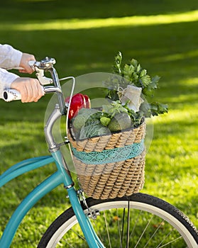 Woman riding a bike with fresh vegetables from market