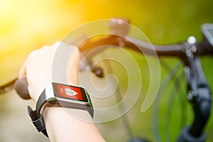 Woman riding a bike with a smartwatch heart rate monitor.