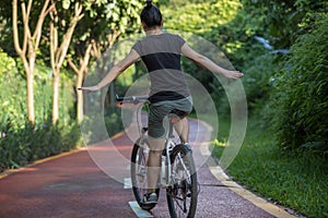 Woman riding a bike on sunny park trail