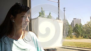 Woman riding on the bus looking out the window and listening to music