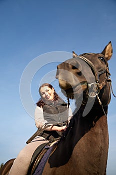 Woman riding a horse in autumn day and blue sky background