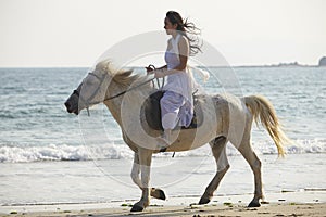 A woman riding horse on beach