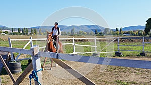 A woman is riding a horse at an outdoor manege