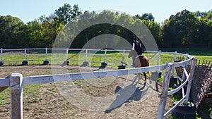 A woman is riding a horse at an outdoor manege