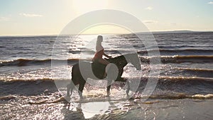 Woman riding on horse at river beach in water sunset light