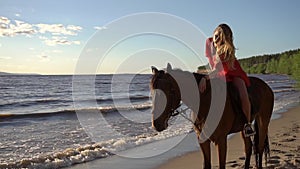 Woman riding on horse at river beach in water sunset light