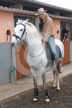 Woman riding a horse in the stables before going for a jog