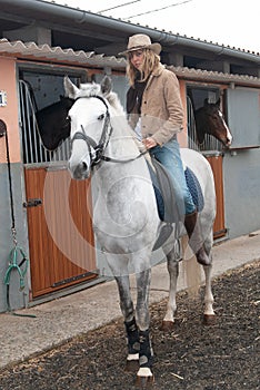 Woman riding a horse in the stables before going for a jog