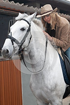 Woman riding a horse in the stables before going for a jog