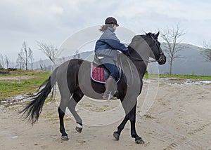 Woman is riding a horse on a training ground