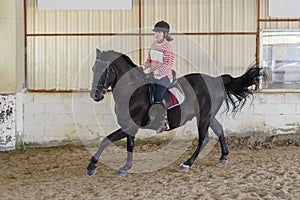 Woman is riding a horse on a training ground