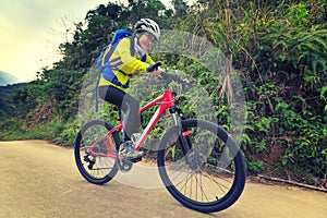 Woman riding mountain bike on forest trail