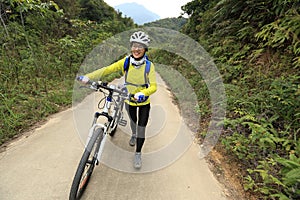 Woman riding mountain bike on forest trail