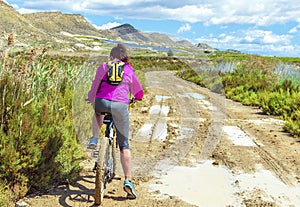 Woman riding a mountain bike by a muddy path of dirt