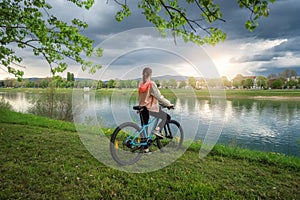 Woman riding a mountain bike near lake and blue sky in spring