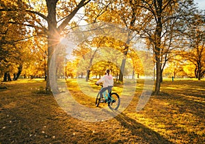 Woman riding a mountain bike and orange trees at sunset in autumn
