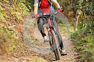 Woman riding mountain bike on outdoor trail in forest