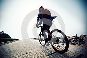 Woman riding mountain bike in the sunrise coast