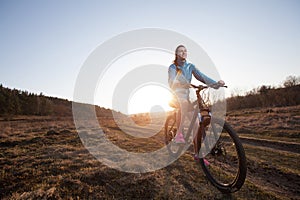 woman riding mountain bike at sunset