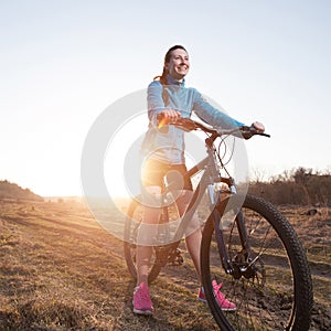 Woman riding mountain bike at sunset