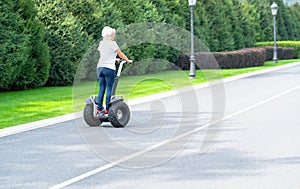 Woman riding personal transporter down long road