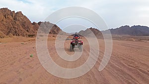 Woman is Riding a Quad Bike in the Desert of Egypt. Dynamic view in motion.
