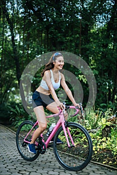 Woman riding a road bike. Portrait of young beautiful woman on pink bike