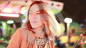 Woman riding on roundabout and beckoning to camera in amusement park