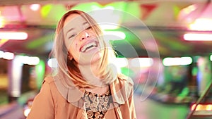 Woman riding on roundabout and beckoning to camera in amusement park