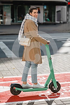 woman riding scooter along bike lane road in city