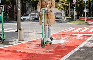 woman riding scooter along bike lane road in city